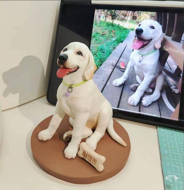 A finished Labrador figurine beside the phone photo used as reference