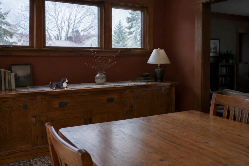 Dining room with an oak built-in buffet holding a small figurine of a senior Bernese Mountain Dog beneath rainy windows
